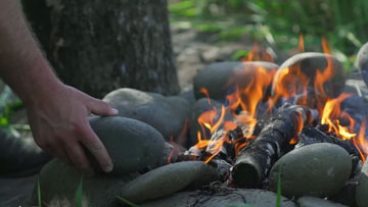 Go with your pallette, taste of elouan - campfire image, hand placing a rock in a fire ring